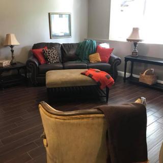 A cozy living room with a sofa, armchair, and coffee table, decorated with colorful throw pillows and lamps.
