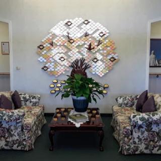 A cozy living room setup featuring floral-patterned couches, a decorative wall art piece, and a vibrant potted plant.