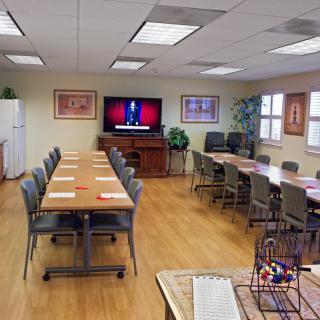 A well-organized meeting room with tables, chairs, and a television on the wall.