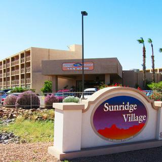 Entrance to Sunridge Village surrounded by desert landscaping and palm trees.