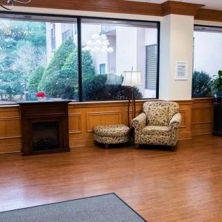 Cozy lobby area with an armchair, ottoman, and large windows overlooking greenery.