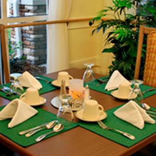 A neatly set dining table with folded napkins, cutlery, and glasses in a restaurant setting.