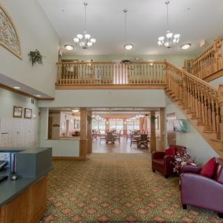 Spacious lobby with a reception desk, elegant staircase, and comfortable seating area.
