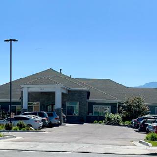 A modern commercial building with a spacious parking lot under clear blue skies.