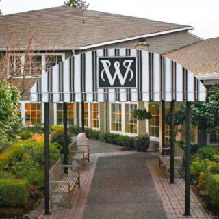Entrance to a building with a striped awning and landscaped garden.