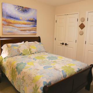 A cozy bedroom with a floral-patterned bedspread and artwork above the bed.