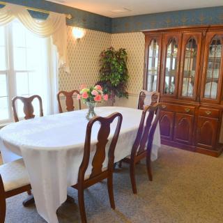 A traditional dining room with a table set for guests and a classic china cabinet.