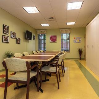 A well-lit conference room with a long table, surrounded by chairs, and decorated walls.