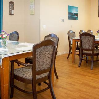 A cozy dining area with neatly arranged tables and chairs on a wooden floor.