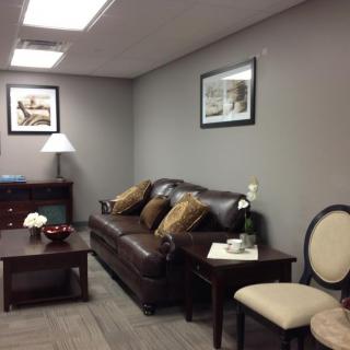 A comfortable waiting room with a sofa, chairs, coffee table, and artwork on the walls.