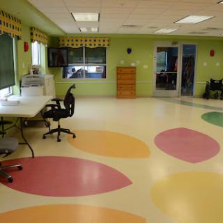 A vibrant playroom featuring colorful flooring and green walls, designed to create a welcoming environment for children.