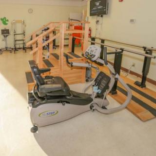 A physical therapy room equipped with exercise machines and parallel bars for rehabilitation.
