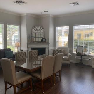A bright and spacious living room with a dining area, featuring large windows, a fireplace, and elegant furniture.