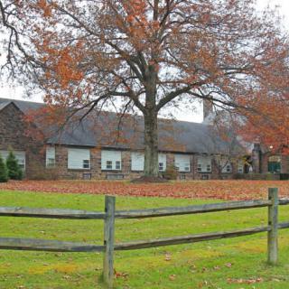 A cozy house surrounded by colorful autumn leaves and a wooden fence.