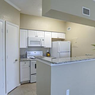 A modern apartment kitchen with white cabinets and appliances.