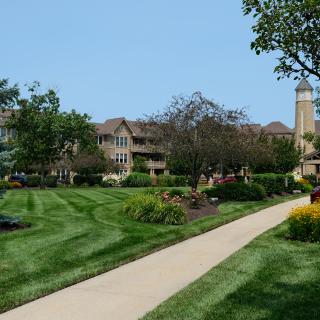 A scenic view of a well-maintained landscape with buildings, lush greenery, and a pathway.