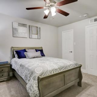 A cozy bedroom featuring a stylish bed with decorative pillows, a ceiling fan, and minimalist artwork.