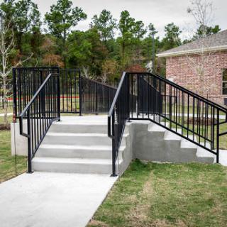 A wheelchair-accessible ramp with handrails leading to a set of stairs.