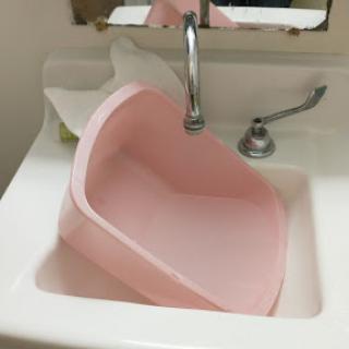 A pink basin awkwardly positioned in a sink, showcasing an unconventional use of kitchen space.