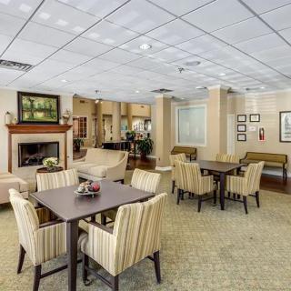 A cozy and elegantly designed lobby seating area with tables, chairs, and a fireplace.