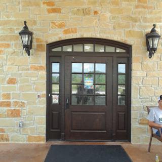 A charming entrance featuring a wooden door flanked by lanterns, set against a textured stone wall.