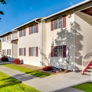 A sunny day view of a residential apartment building with landscaped surroundings.