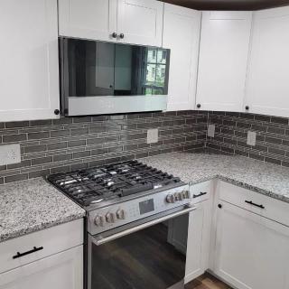A modern kitchen with white cabinets and stainless steel appliances.