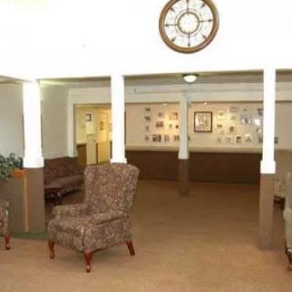 A view of a lobby area featuring armchairs, a large wall clock, and decorative items on the walls.