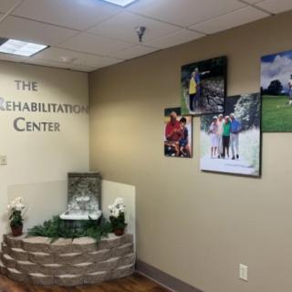 Interior view of a rehabilitation center with decorative photos and a small indoor fountain.