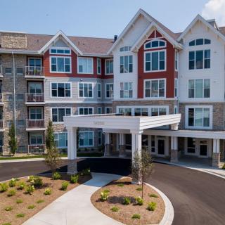 A modern residential building with an entrance driveway and landscaped surroundings.