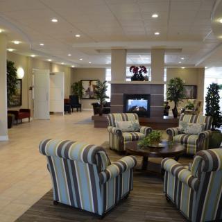 A spacious hotel lobby featuring a seating area with striped chairs and a central fireplace.