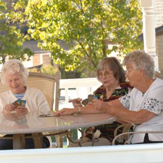 A group of elderly individuals enjoying a card game on a porch.