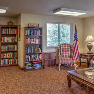 Cozy library corner with bookshelves, an armchair, and a window view.