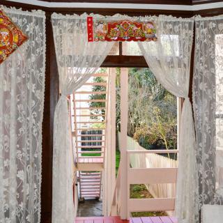 A cozy interior with lace curtains framing a doorway that opens to an outdoor view.