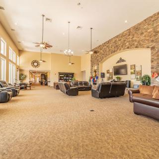 A spacious living room with comfortable seating and elegant decor, featuring a stone accent wall and large windows.