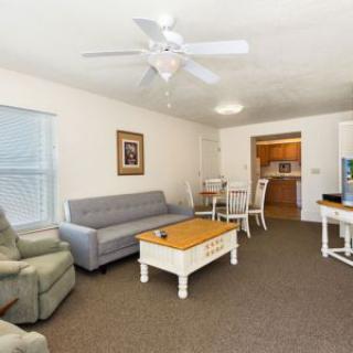 A cozy living room with a sofa, armchair, and coffee table adjacent to a dining area.