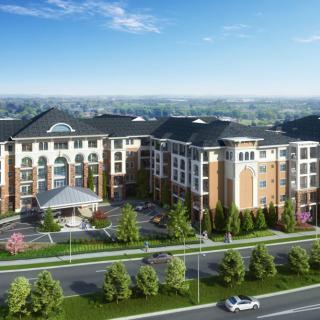 Aerial view of a modern apartment complex with landscaped surroundings and a nearby road.