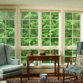 A cozy living room with large windows offering a scenic view of lush greenery.