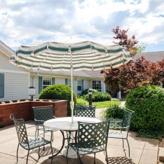 A cozy patio setup with a table, chairs, and a sun umbrella in a garden setting.