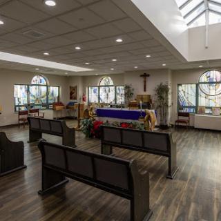 A serene interior of a chapel featuring pews, an altar, and ample natural light.