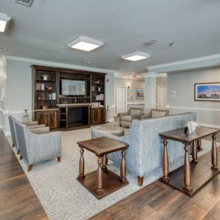 A spacious living room with modern furniture, including a sofa and coffee tables, centered around a fireplace and surrounded by bookshelves.