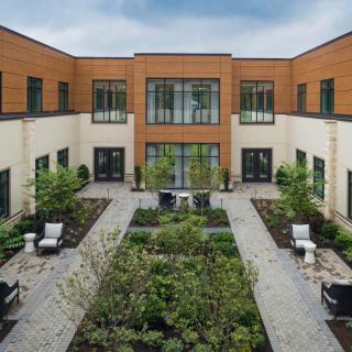 A modern courtyard featuring lush landscaping and outdoor seating.