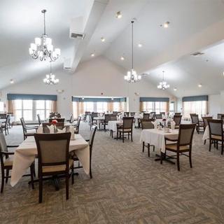 A spacious dining area with neatly arranged tables and chairs, illuminated by elegant chandeliers.