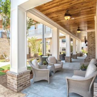 A beautiful covered patio with wicker seating and lush landscaping.