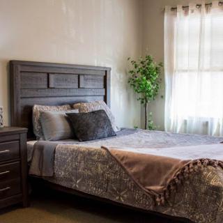 A cozy bedroom featuring a stylish bed with decorative pillows and a bedside table.
