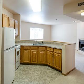 An apartment kitchen with wooden cabinets and standard appliances.