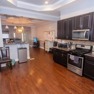Spacious kitchen with modern appliances and hardwood flooring leading to a dining area.