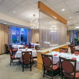An elegant restaurant dining area with neatly arranged tables and chairs, adorned with a chandelier.