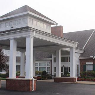 The image shows the entrance of a large building with prominent white columns and a covered porch.