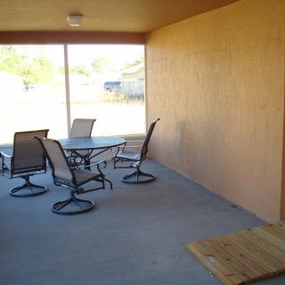 A covered patio with a table and chairs, enclosed by a screen.